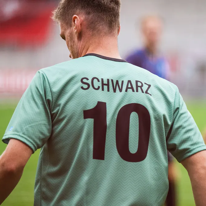 Un joueur porte un maillot de football vert menthe avec le numéro 10 et le nom 'SCHWARZ' au dos.