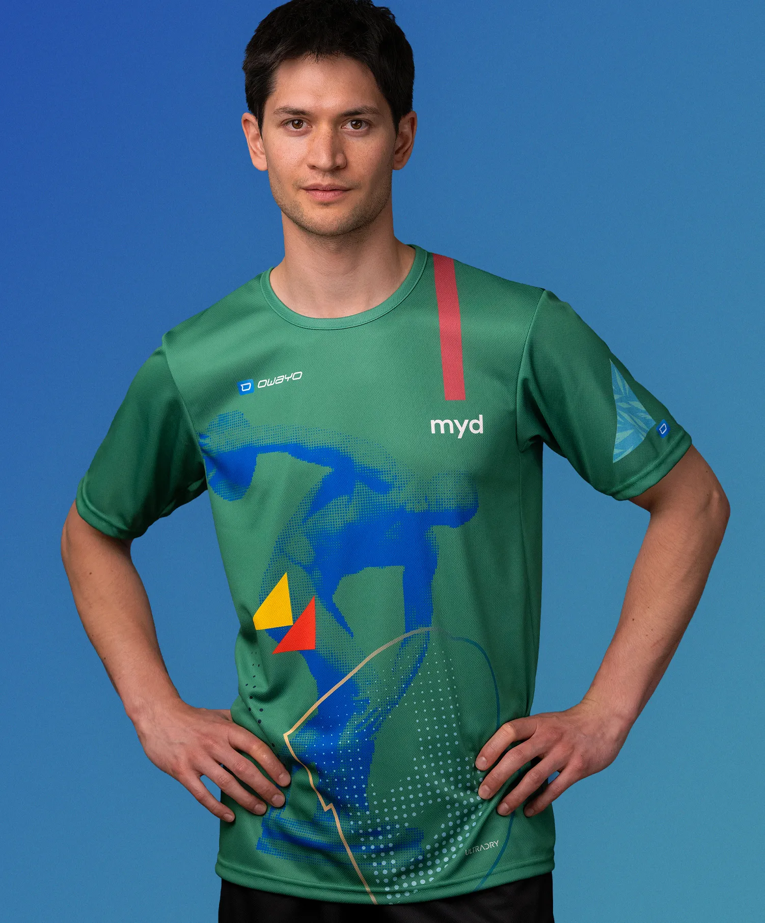 Un homme portant un maillot de sport vert personnalisé de owayo avec un motif graphique bleu, jaune et rouge et l'inscription 'myd' sur la poitrine.