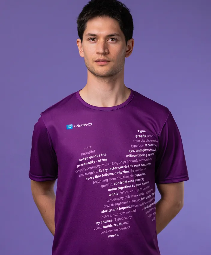 Un homme porte un t-shirt de sport violet avec un texte typographique sur le devant, sur un fond violet.