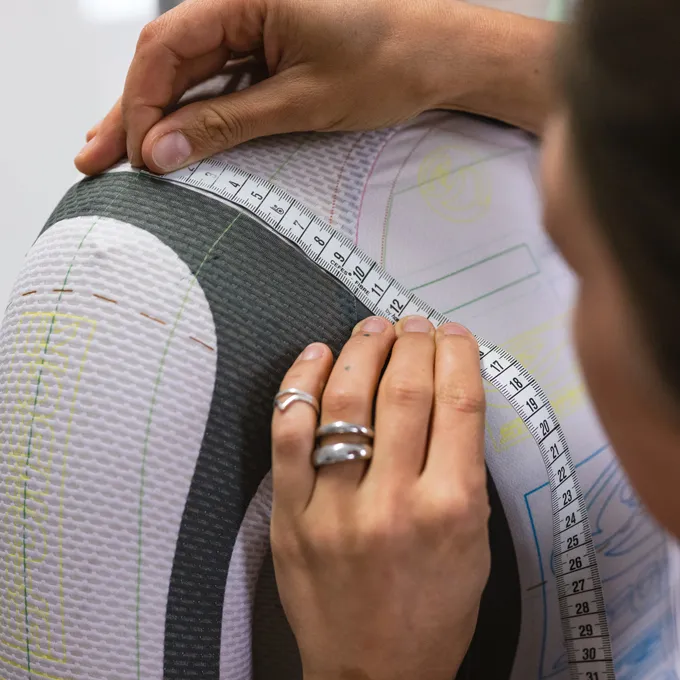 Une personne mesure le haut du bras d'un vêtement de sport sur mesure d'owayo, marqué de lignes de patron.